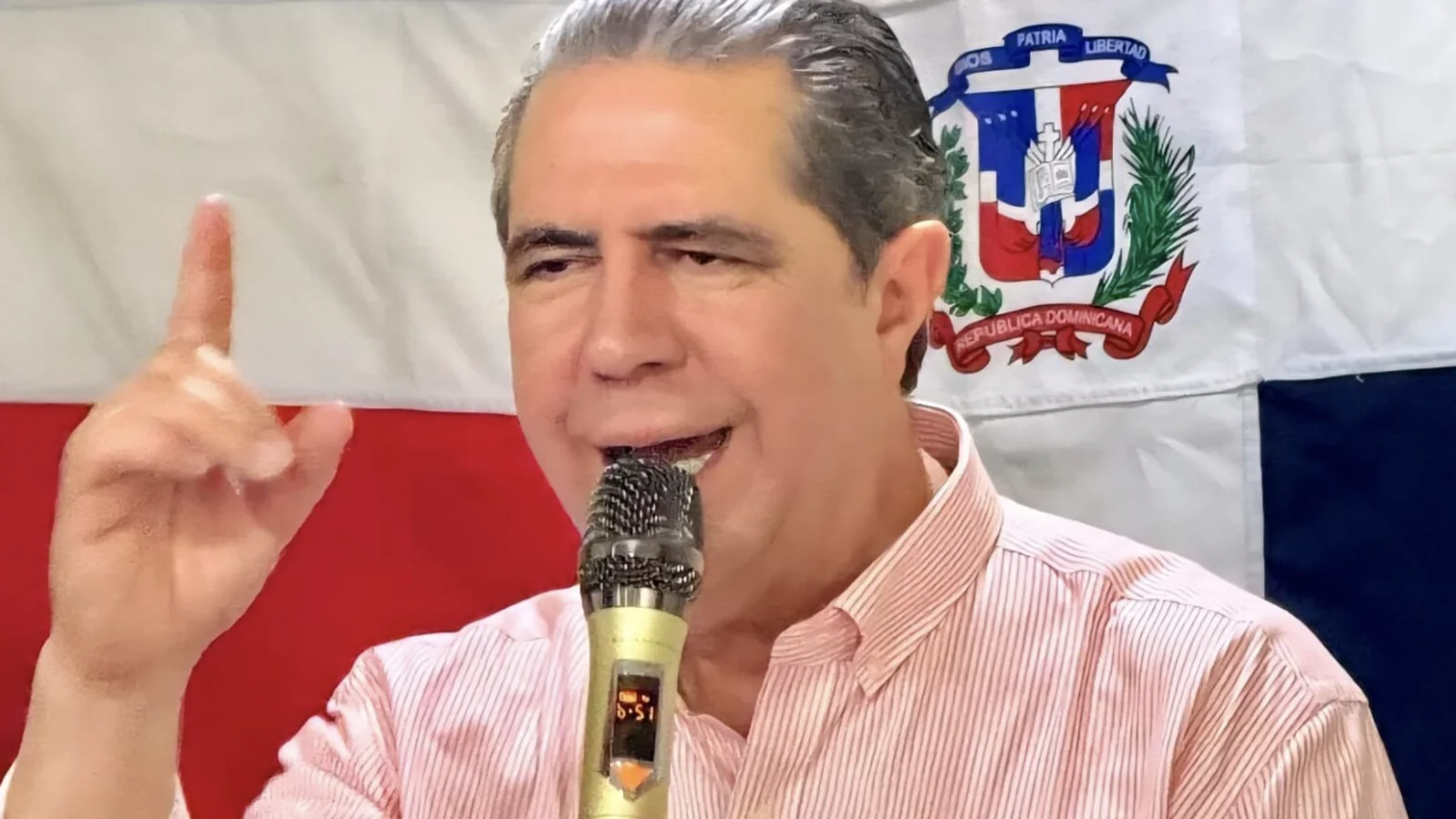 Francisco Javier García habla con una bandera dominicana de fondo.